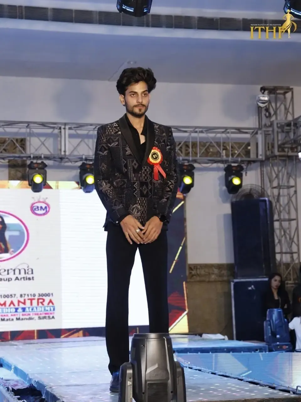 A contestant in an embroidered jacket at the end of the ramp