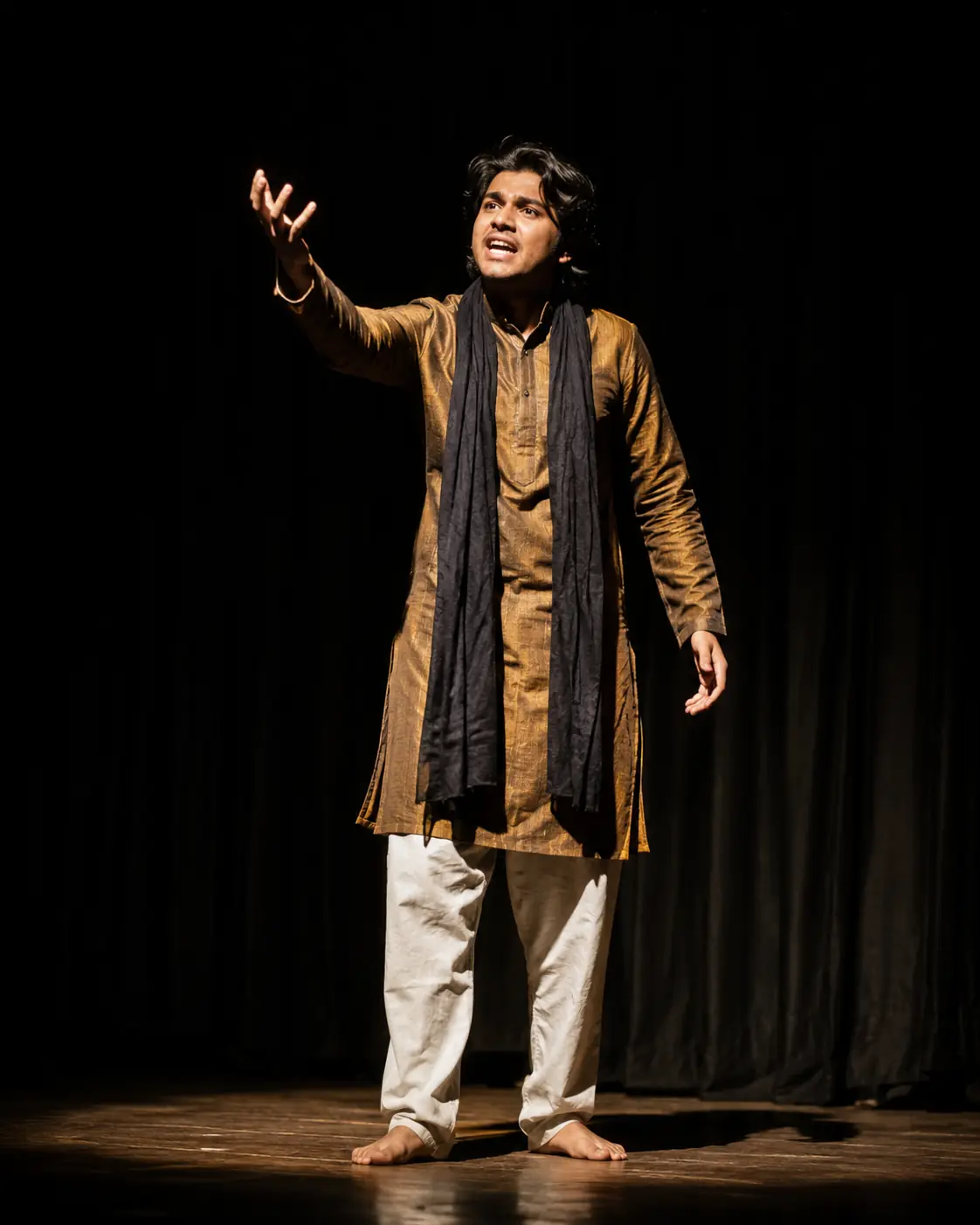 A performer mid-monologue under a single spotlight on a bare stage