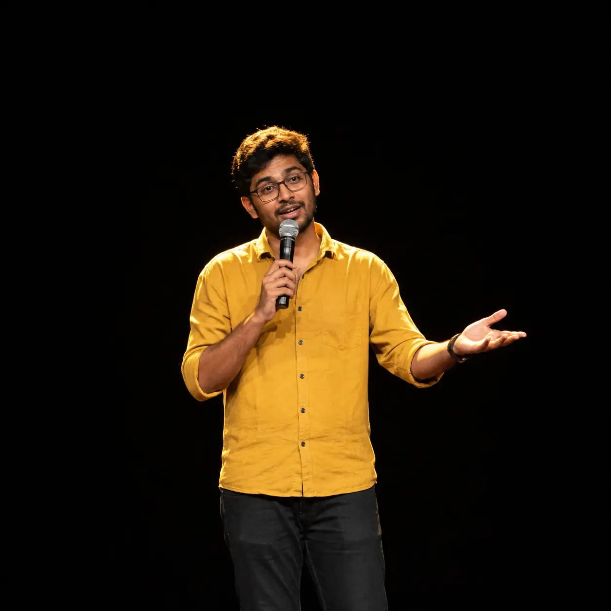 A performer alone with a handheld microphone in a spotlight