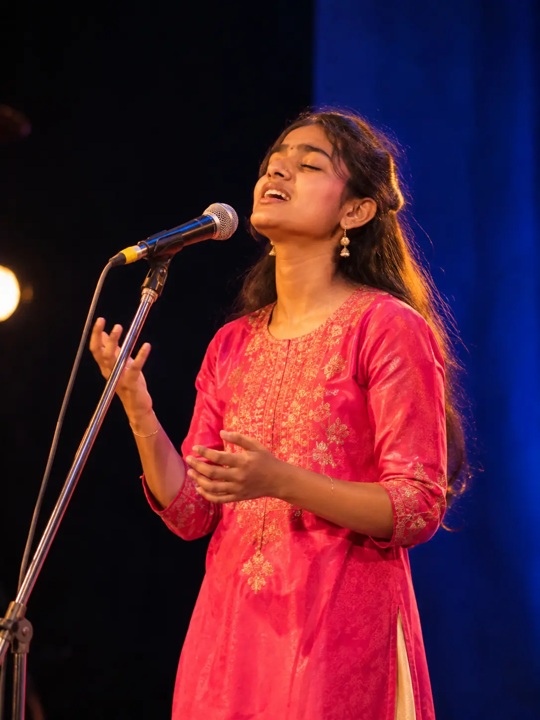 A young singer performing at a microphone stand under stage lights